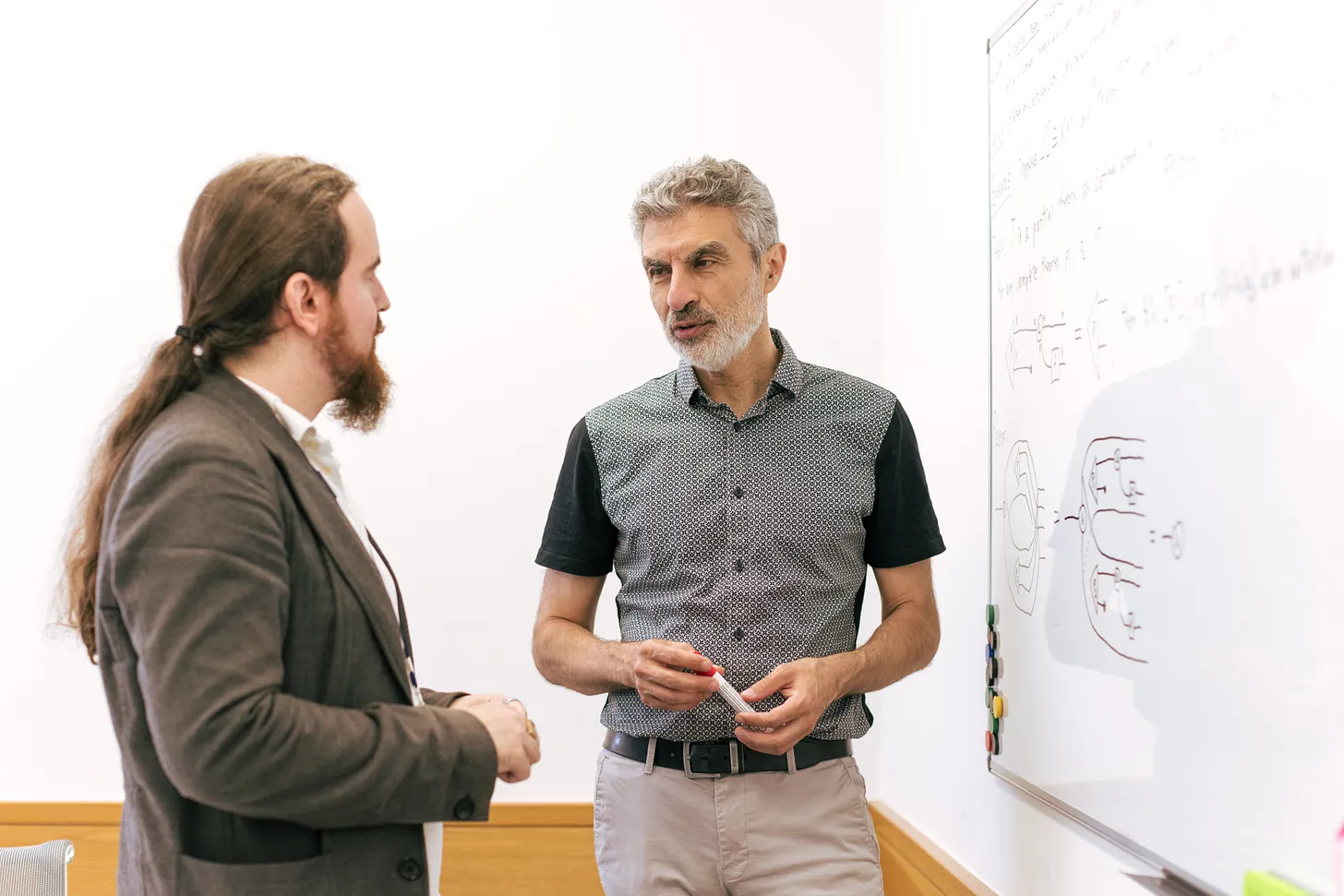A photo of Yoshua Bengio and Davidad Dalrymple standing in front of a white board